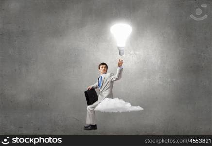 Young businessman sitting on cloud and thinking something over. Waiting for inspiration