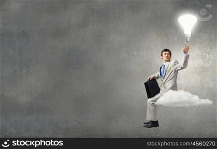 Young businessman sitting on cloud and thinking something over. Waiting for inspiration