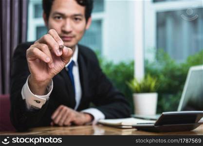 Young businessman sitting on desk drawing concept at office