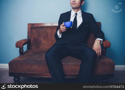 Young businessman sitting on sofa and drinking coffee