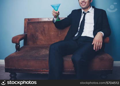 Young businessman sitting on sofa with cocktail glass