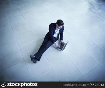 Young businessman sitting on the floor using his laptop