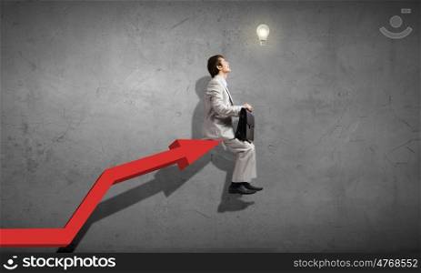 Young businessman sitting on top of growing graph. On top of success