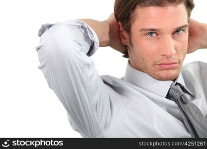 Young businessman sitting with arms behind head.