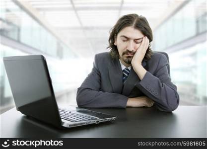 young businessman sleeping on the laptop at the office