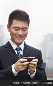 Young Businessman Smiling and Using a Smart Phone