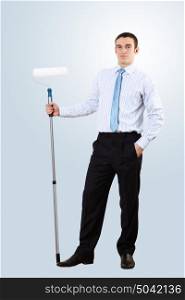 Young businessman standing against blank wall with brush