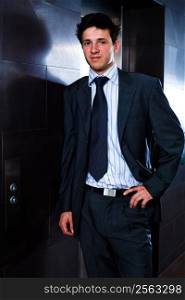 Young businessman standing at office in front of elevator.