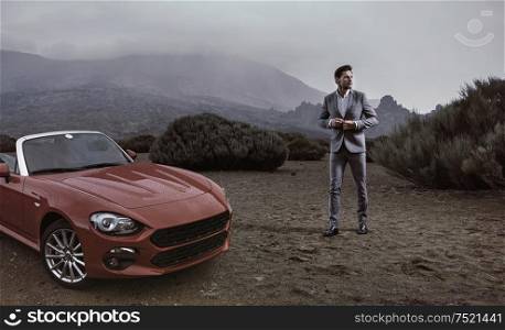 Young businessman standing next to the luxurious convertible