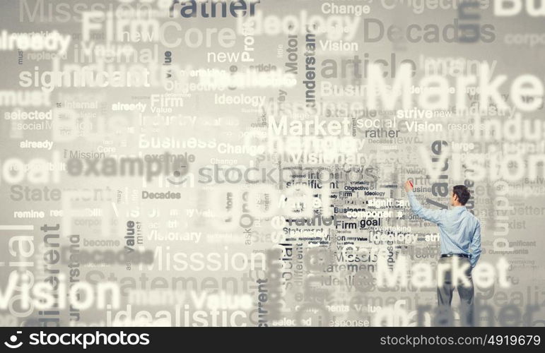 Young businessman standing with back and writing different words on wall. Copyright concept