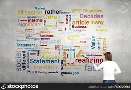Young businessman standing with back and writing different words on wall. Copyright concept