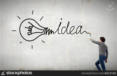 Young businessman standing with back and writing different words on wall. Idea concept