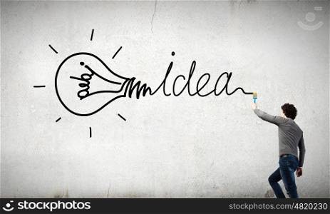 Young businessman standing with back and writing different words on wall. Idea concept
