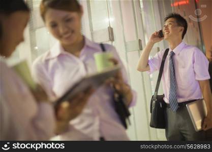 Young businessman talking on the phone, coworkers discussing on the foreground