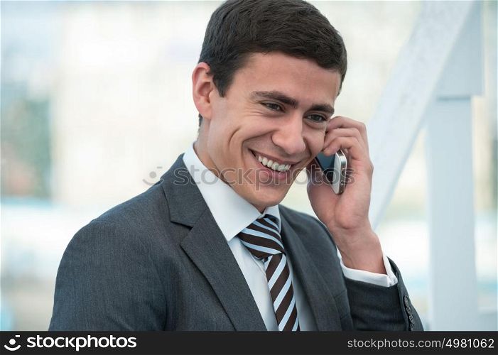 Young businessman talking phone outside office building or at airport