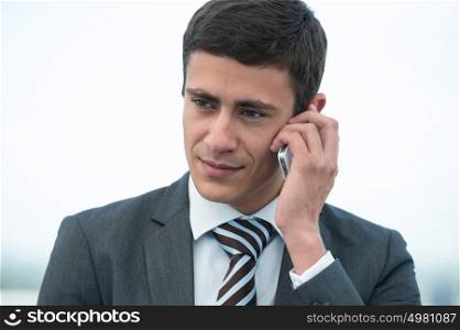 Young businessman talking phone outside office building or at airport