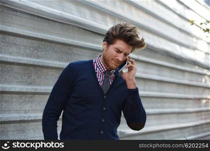 Young businessman talking smartphone phone on the street metal fence