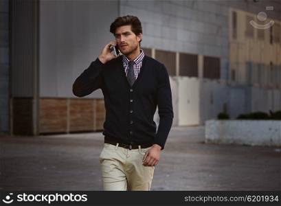 Young businessman talking smartphone phone walking on the street