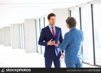 Young businessman talking with male colleague in new office