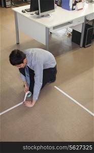 Young Businessman taping up the floor in the office
