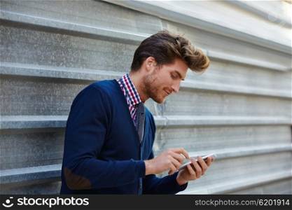 Young businessman texting smartphone phone on the street metal fence
