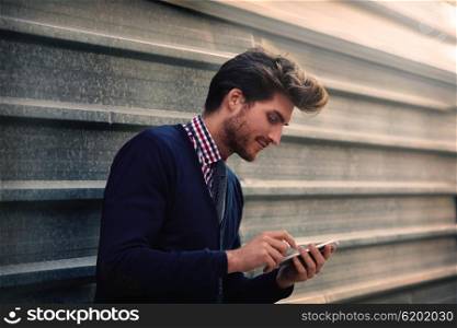 Young businessman texting smartphone phone on the street metal fence