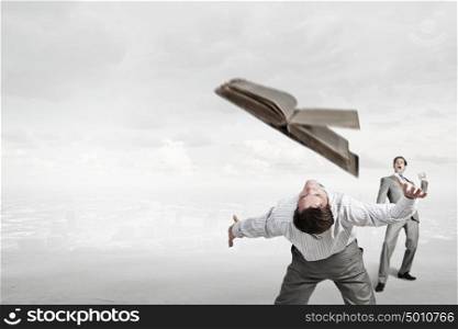 Young businessman trying to evade from thrown book