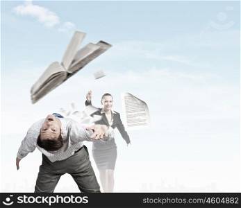 Young businessman trying to evade from thrown book. Two business people fighting with each other