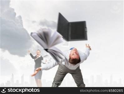 Young businessman trying to evade from thrown laptop