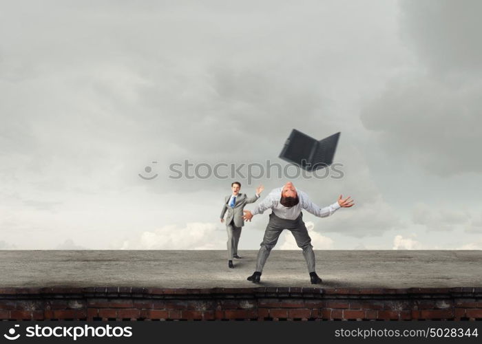 Young businessman trying to evade from thrown laptop. Two business people fighting with each other