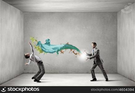 Young businessman trying to evade from thrown splashes. Two business people fighting with each other