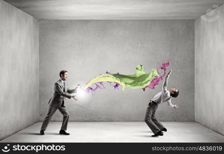 Young businessman trying to evade from thrown splashes. Two business people fighting with each other