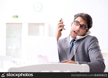 Young businessman trying to work from home caring after newborn baby. Young businessman trying to work from home caring after newborn