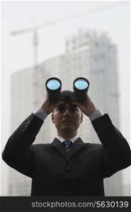 Young Businessman Using Binoculars and Looking into the Distance, Low Angle View