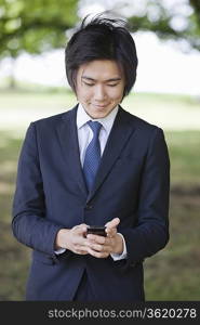 Young businessman using cell phone at park