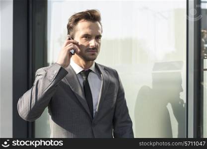 Young businessman using cell phone outside office building