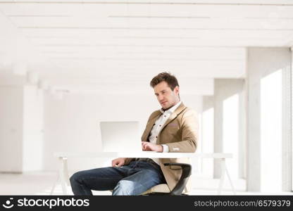 Young businessman using laptop at desk in office