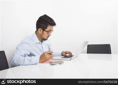 Young businessman using laptop in office