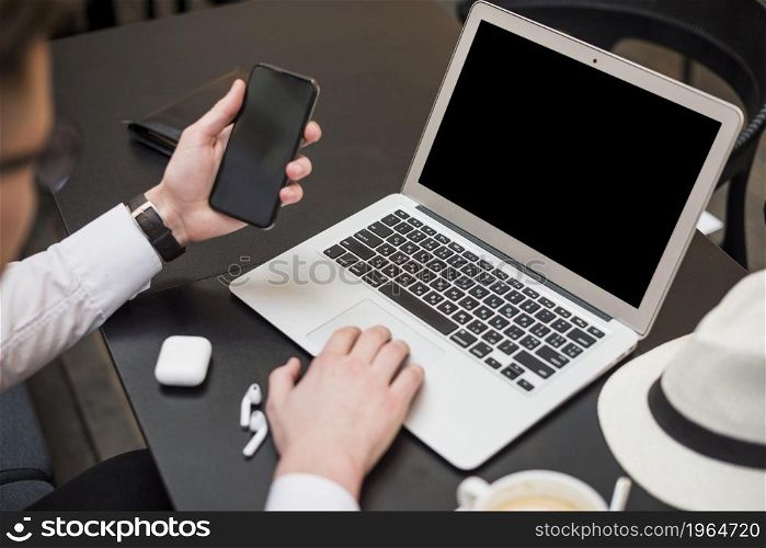 young businessman using laptop looking smartphone screen. High resolution photo. young businessman using laptop looking smartphone screen. High quality photo
