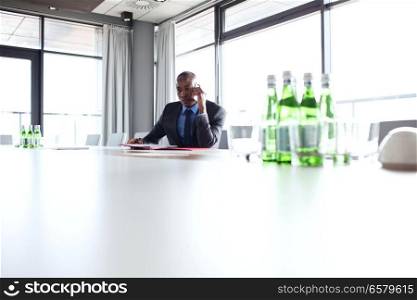 Young businessman using mobile phone at conference table