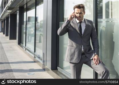 Young businessman using mobile phone outside office