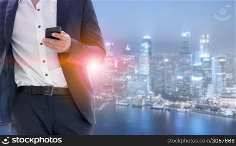 Young businessman using mobile phone with modern city buildings background. Future telecommunication technology and internet of things ( IOT ) concept.. Internet of things - Telecommunication Technology