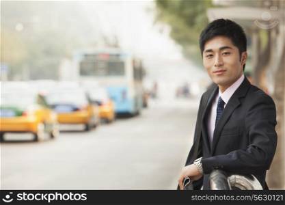 Young businessman waiting at the bus stop for the bus