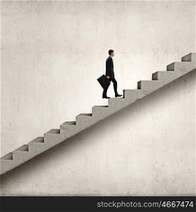 Young businessman walking up on staircase representing success concept. Up the career ladder