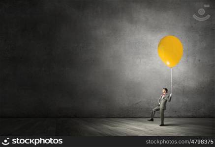 Young businessman walking with colorful balloon on rope