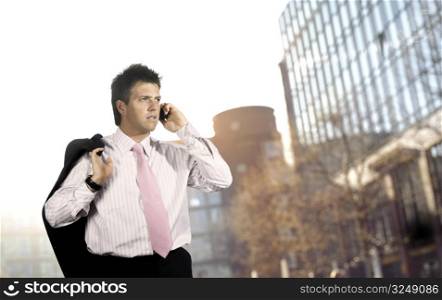 Young businessman walks and talks on a mobile phone, outdoor portrait.