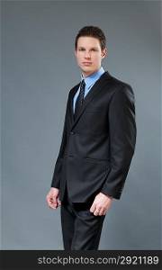Young businessman wearing classic dark suit. Half-turn studio shot. One of a series.
