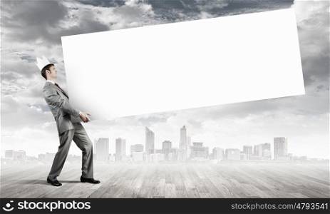 Young businessman wearing crown and carrying white blank banner. Place for text. Banner for your ad