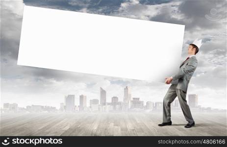 Young businessman wearing crown and carrying white blank banner. Place for text. Banner for your ad