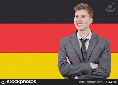 Young businessman with arms crossed over German flag